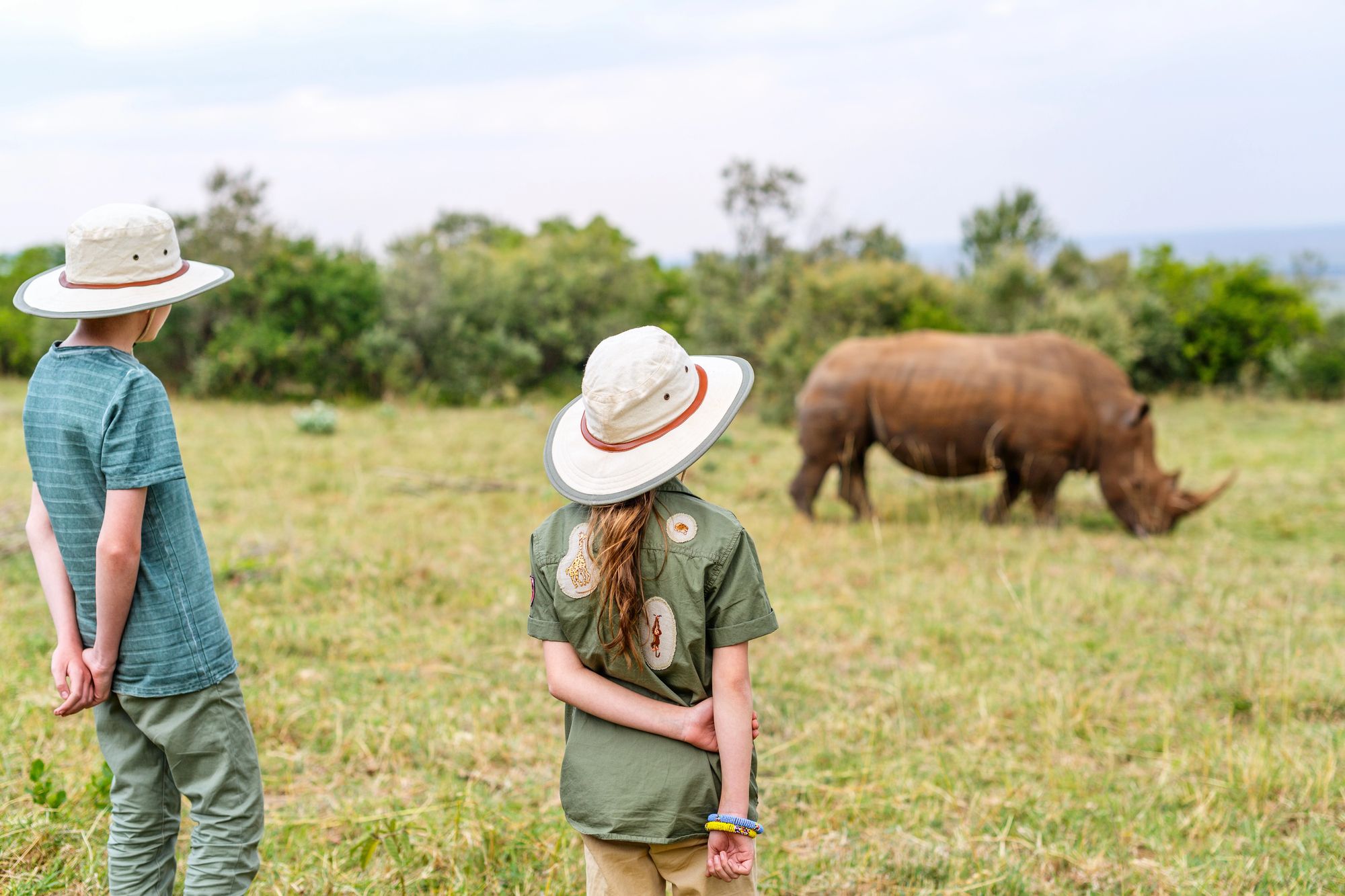 Children in safari hats watching a rhino